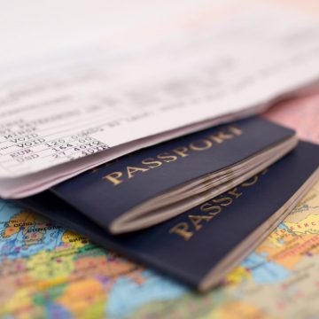 A boarding pass and two passports resting on top of a colourful world map.