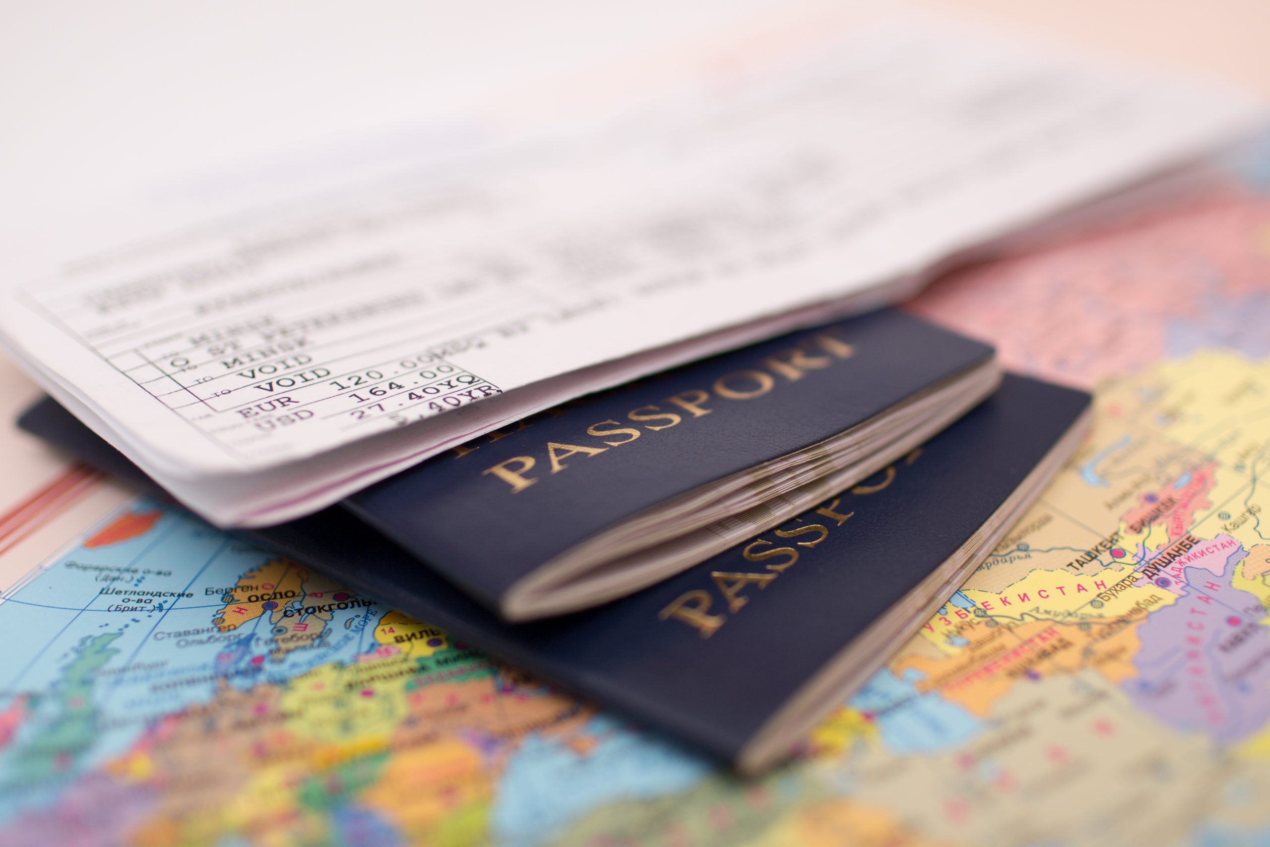 A boarding pass and two passports resting on top of a colourful world map.