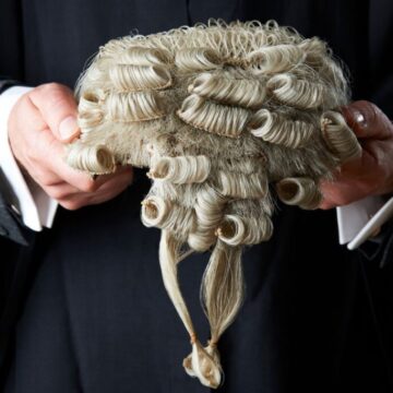 A barrister clutching his white wig in his hands to help illustrate Barristers First's blog answering the question, 'what is a direct access barrister?'.